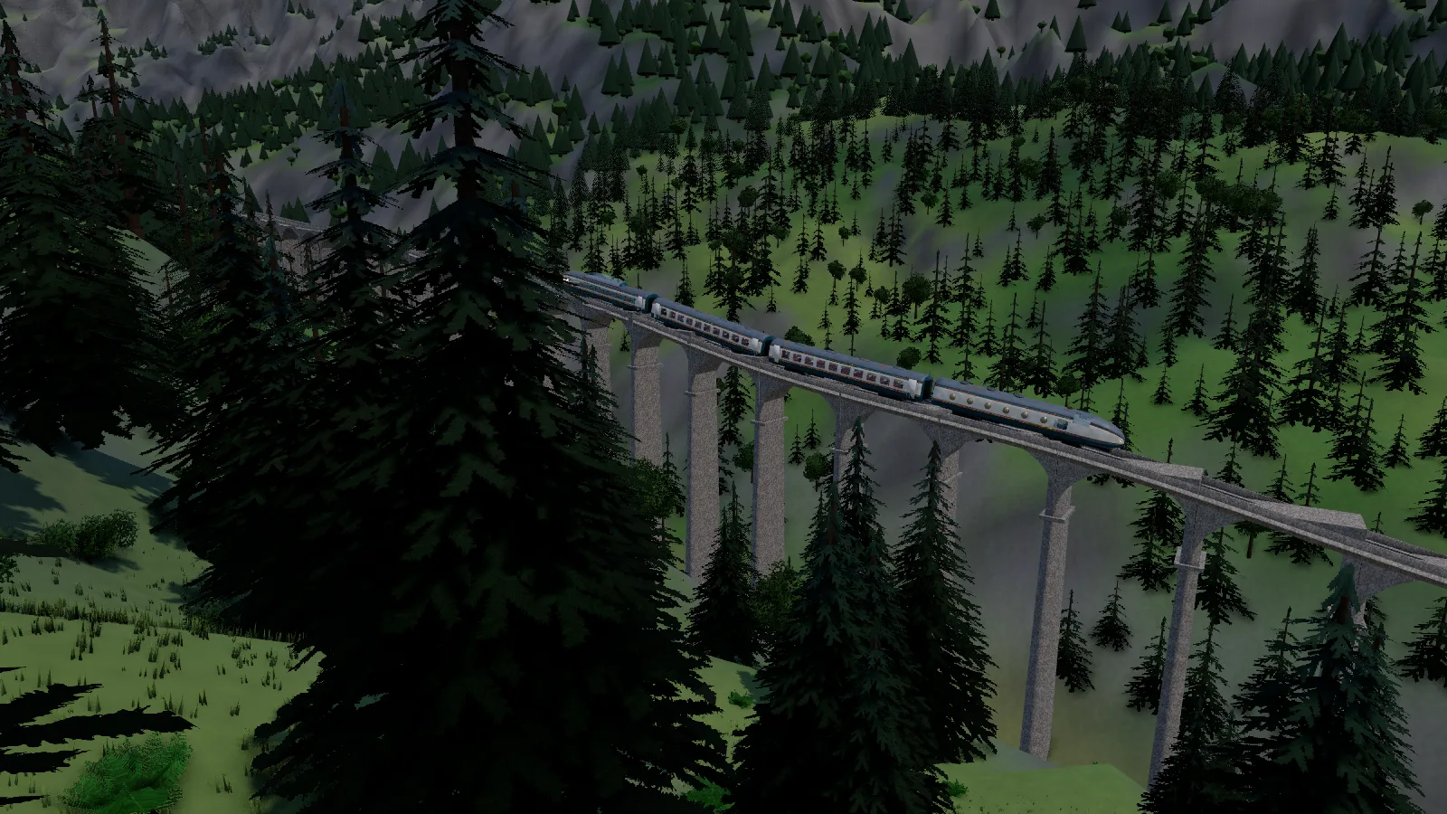 The four-car train crosses a curving stone viaduct over a wooded gorge, with grey mountains behind.
