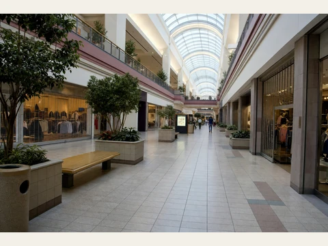 The skylit mall concourse, with planters, benches and storefronts.