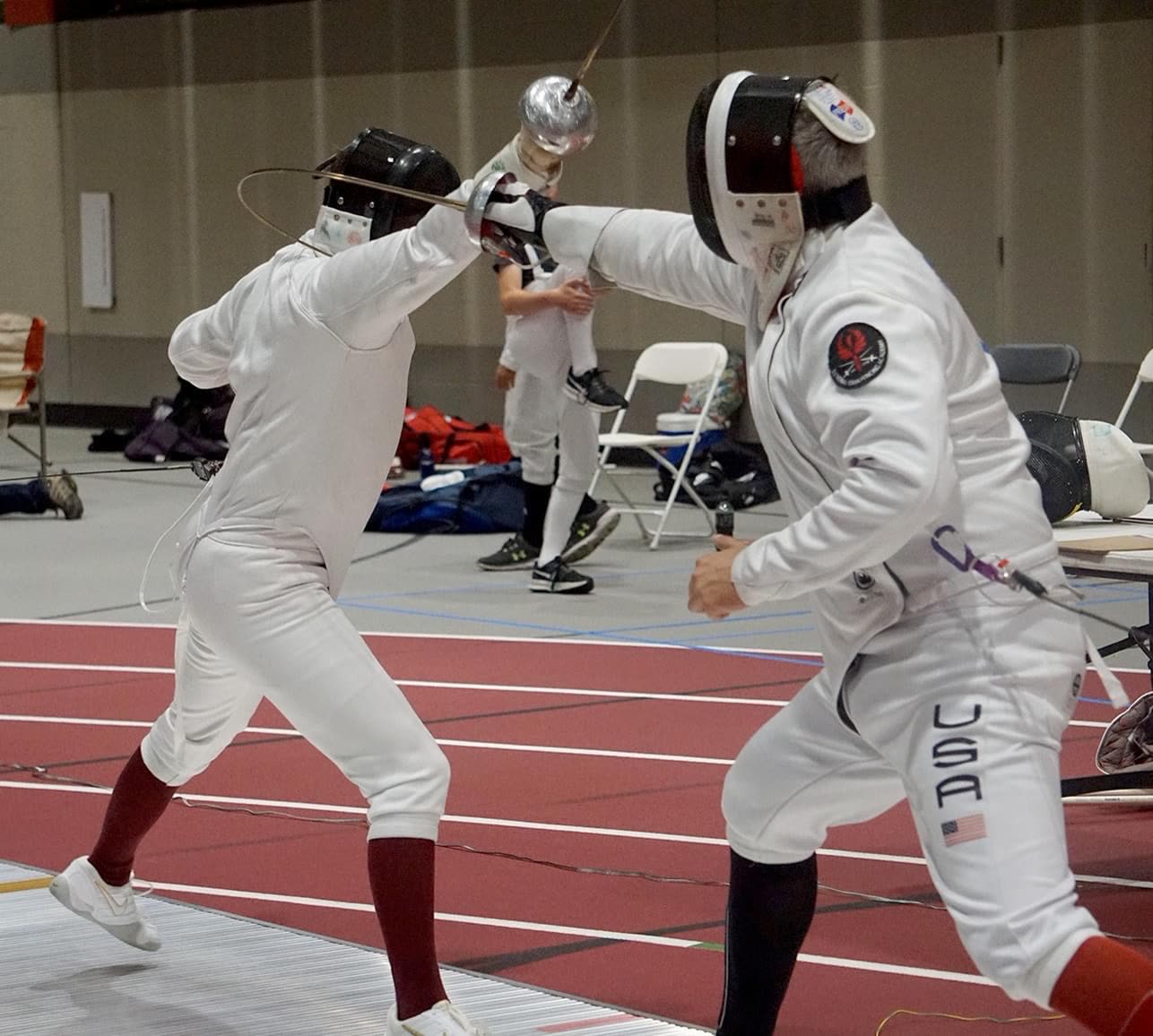 Eric Rhea (right) attacking with an extended épée against an opponent mid-bout