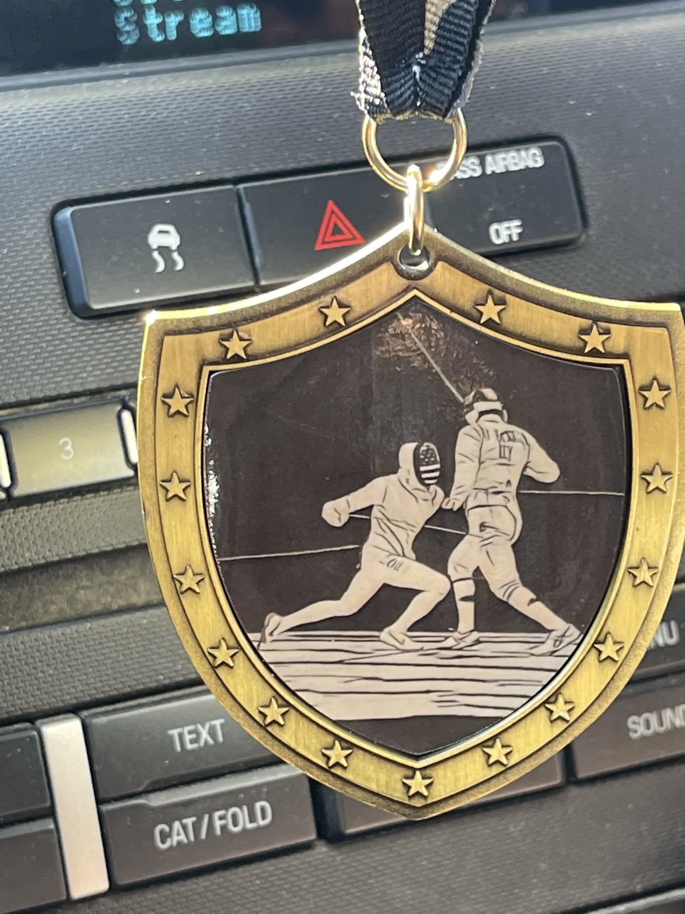 Close-up of the Iowa Games gold medal showing two engraved fencers